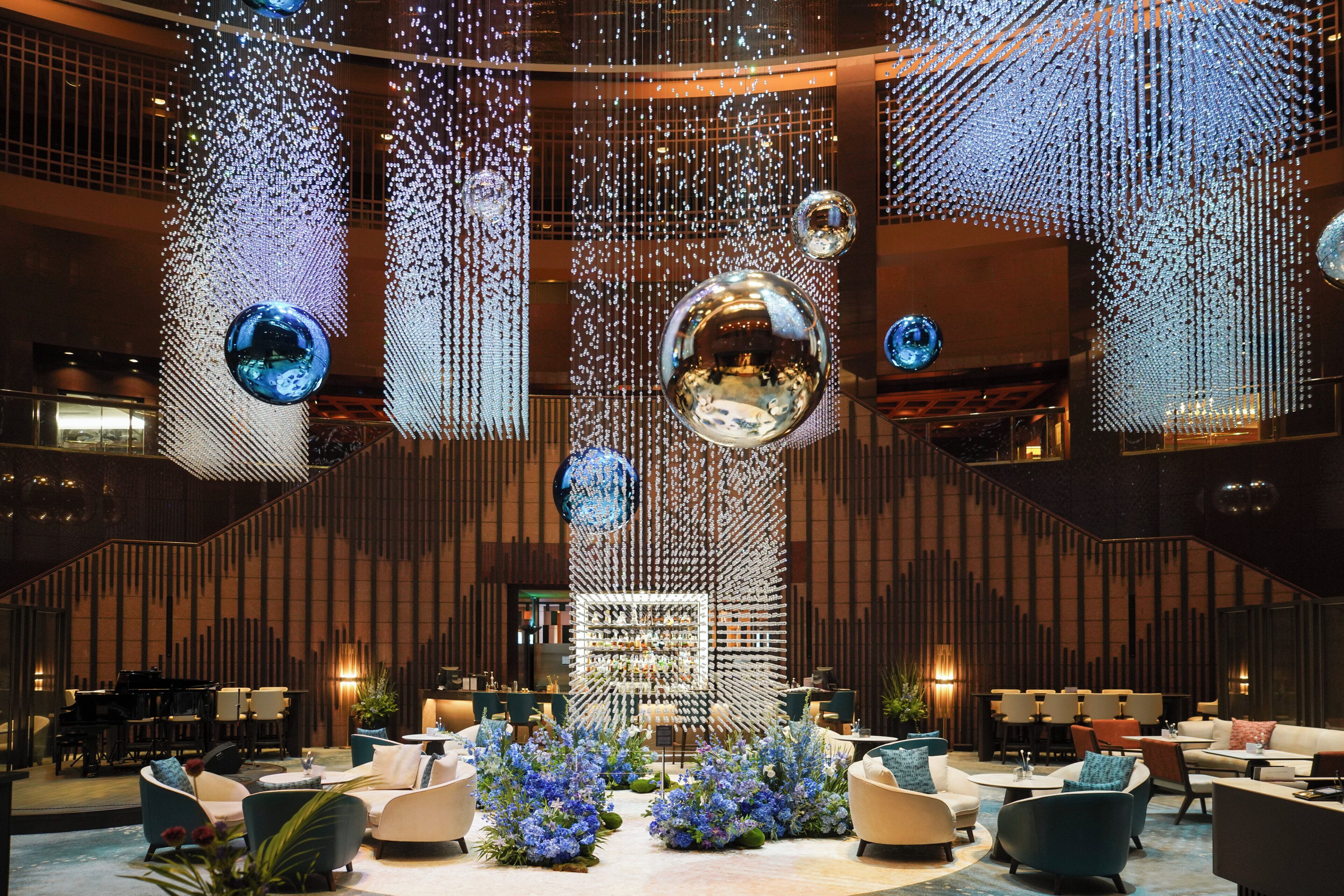 A lobby with seating areas, a reception desk, and decorative elements including hanging ornaments and a central column.