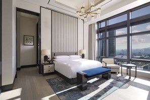 A modern hotel room with a large bed, bedside tables, a bench, a chair, and a view of the city through large windows. - Grand InterContinental Seoul Parnas by IHG (Seoul)