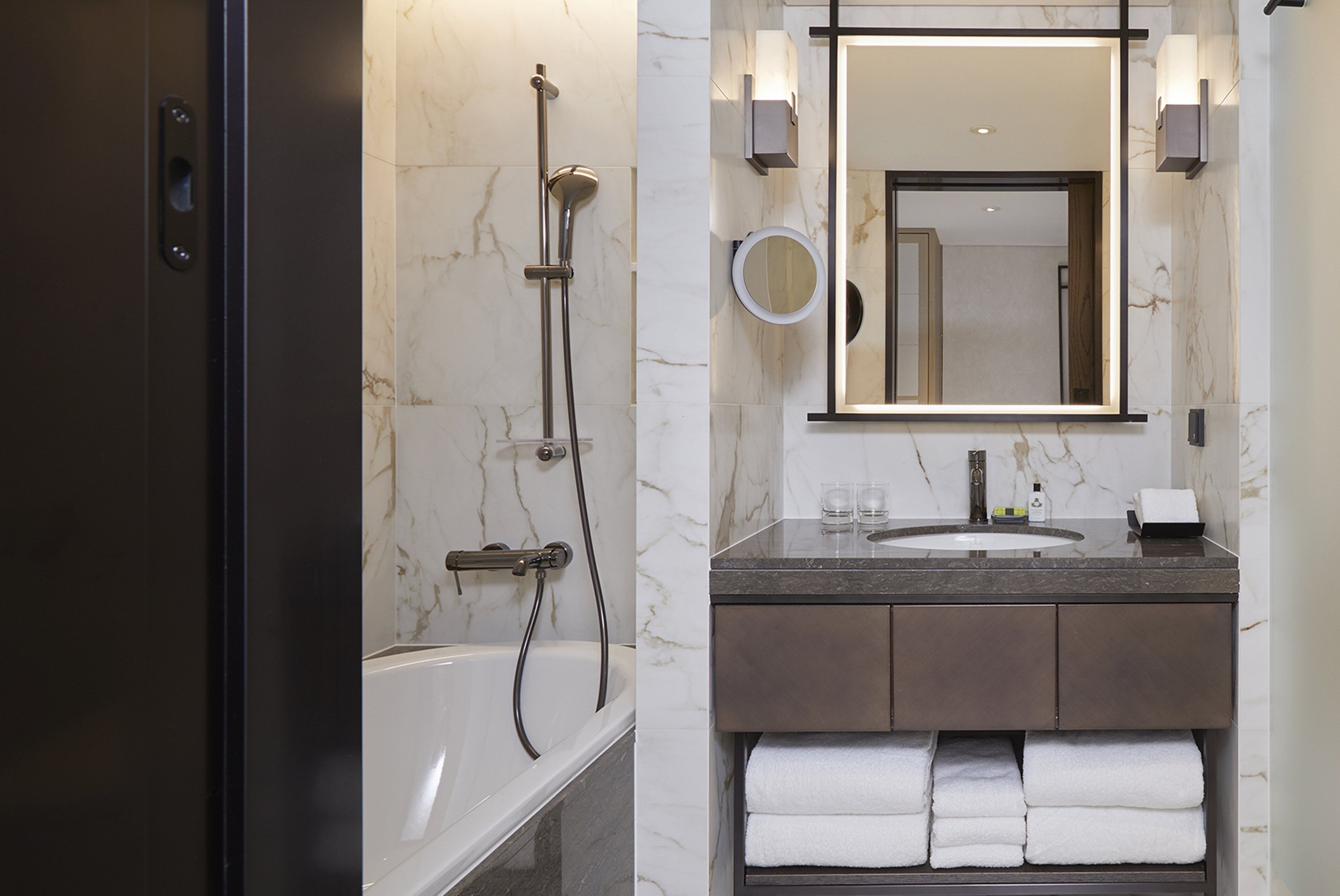 Un baño moderno con bañera, ducha, lavabo y espejo.