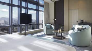Una habitación de hotel moderna con una cama grande, dos sillones, una mesita y un televisor.