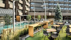 An outdoor pool area with lounge chairs and tables, surrounded by a building with multiple floors and windows. - Delta Hotels by Marriott Quebec (Québec City)