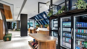 A modern hotel lobby with a wooden reception desk, seating area, and refrigerated beverage dispensers. - Delta Hotels by Marriott Quebec (Québec City)