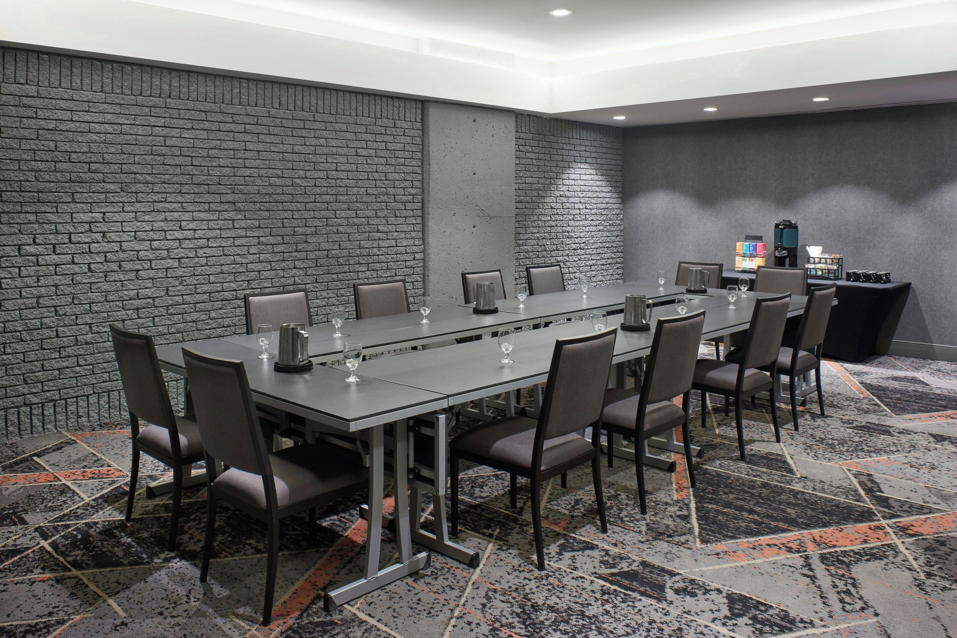 Un salón de conferencias con una mesa larga, sillas y una estación de café.