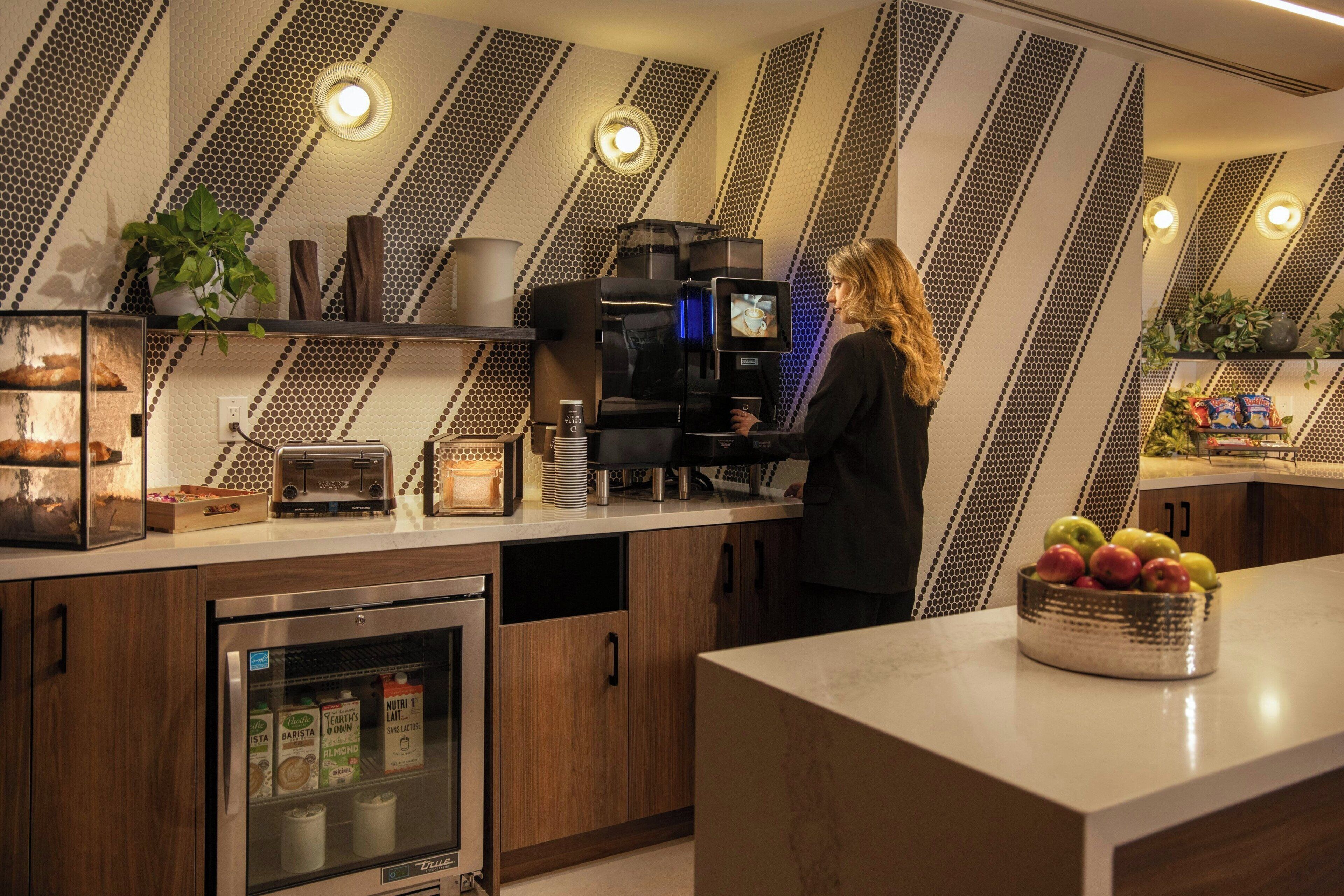 A modern kitchen with a built-in coffee machine, a refrigerator, and a microwave.