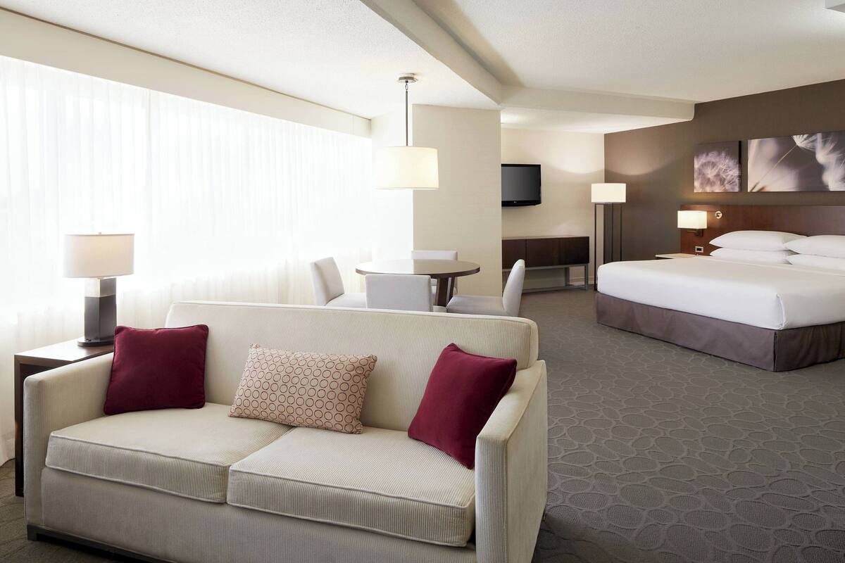 A hotel room with a sofa, a bed, a desk, and a TV.