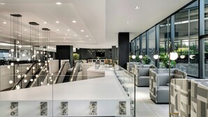 A modern hotel lobby with a central reception desk, seating areas, and a glass partition. - Delta Hotels by Marriott Quebec (Québec City)