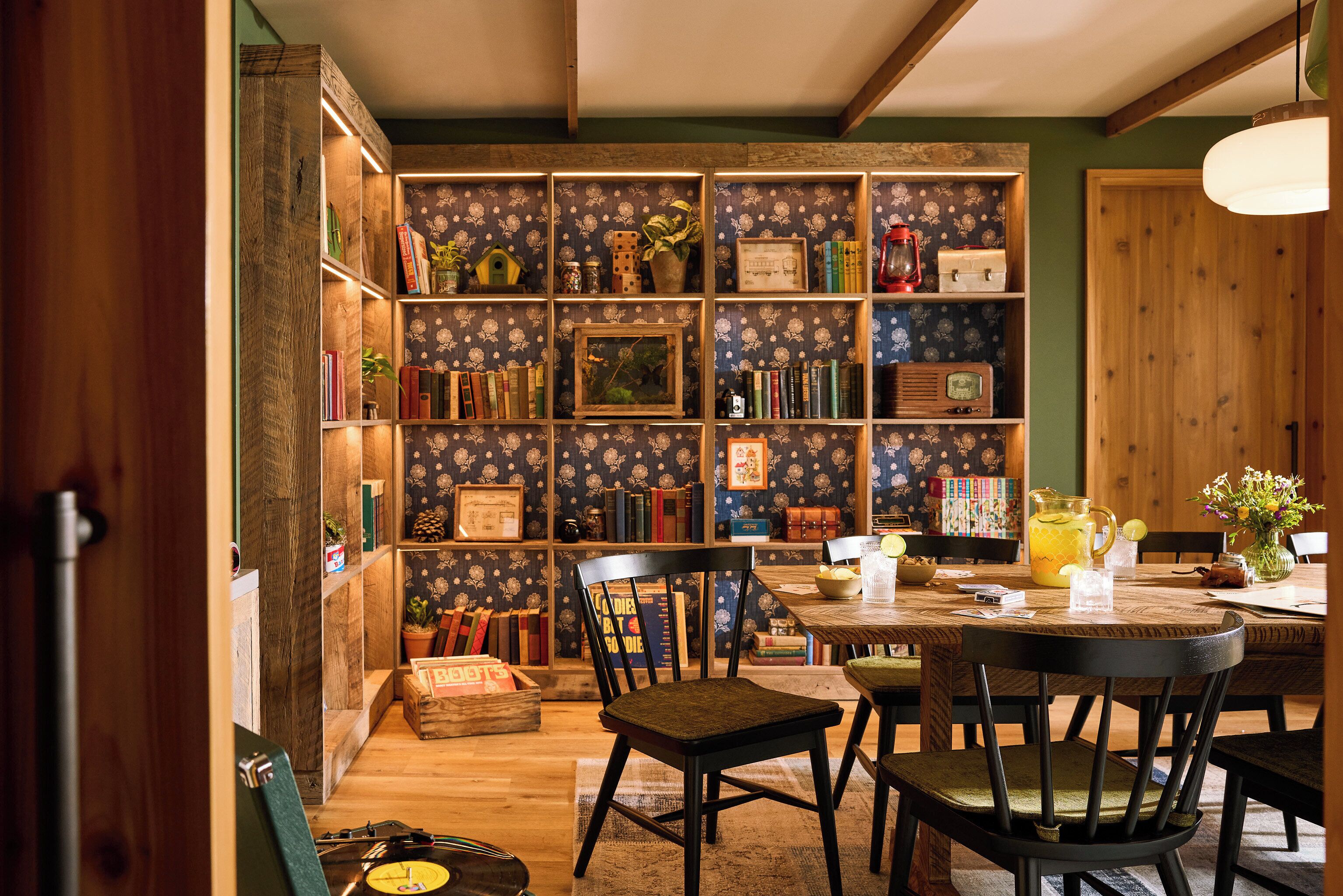 Eine gemütliche Leseecke mit Bücherregal, Holztisch und zwei Stühlen.