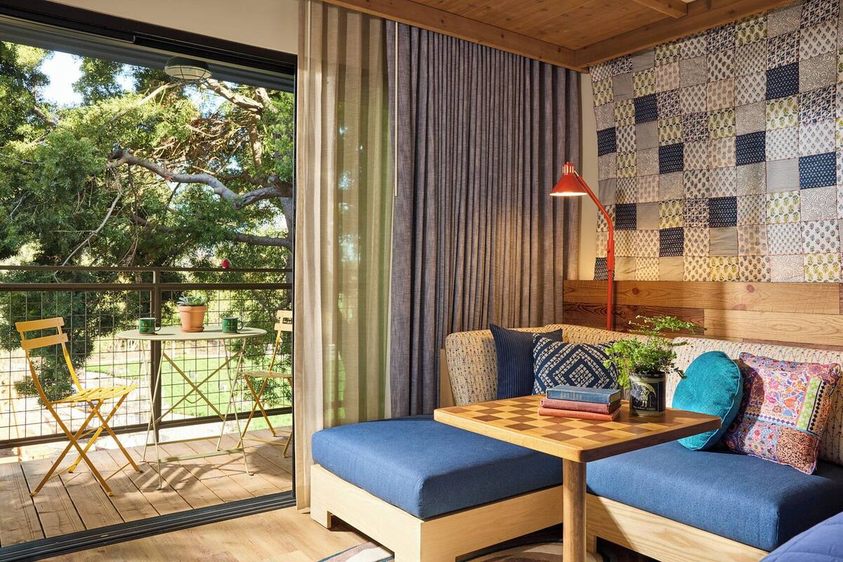 A cozy room with a wooden bench, a small table, and a view of greenery outside.