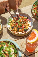 Una mesa con un plato de comida, un vaso de bebida y un bol de ensalada.