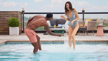 A man and a woman by a pool with a lounge area in the background.