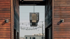 Una terraza de madera con piscina, mobiliario exterior e iluminación colgante.
