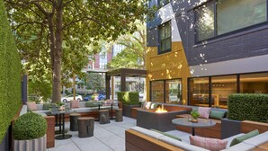 Un espacio al aire libre con mobiliario moderno, un brasero y vistas a la ciudad.