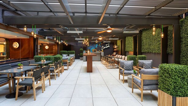 Un restaurante moderno con zona de bar, asientos con sillas acolchadas y mesas, y una pared verde con el letrero 'Doutai'.