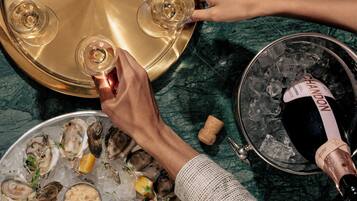 A table with oysters, lemon slices, and sauces, and a bottle of champagne being poured.