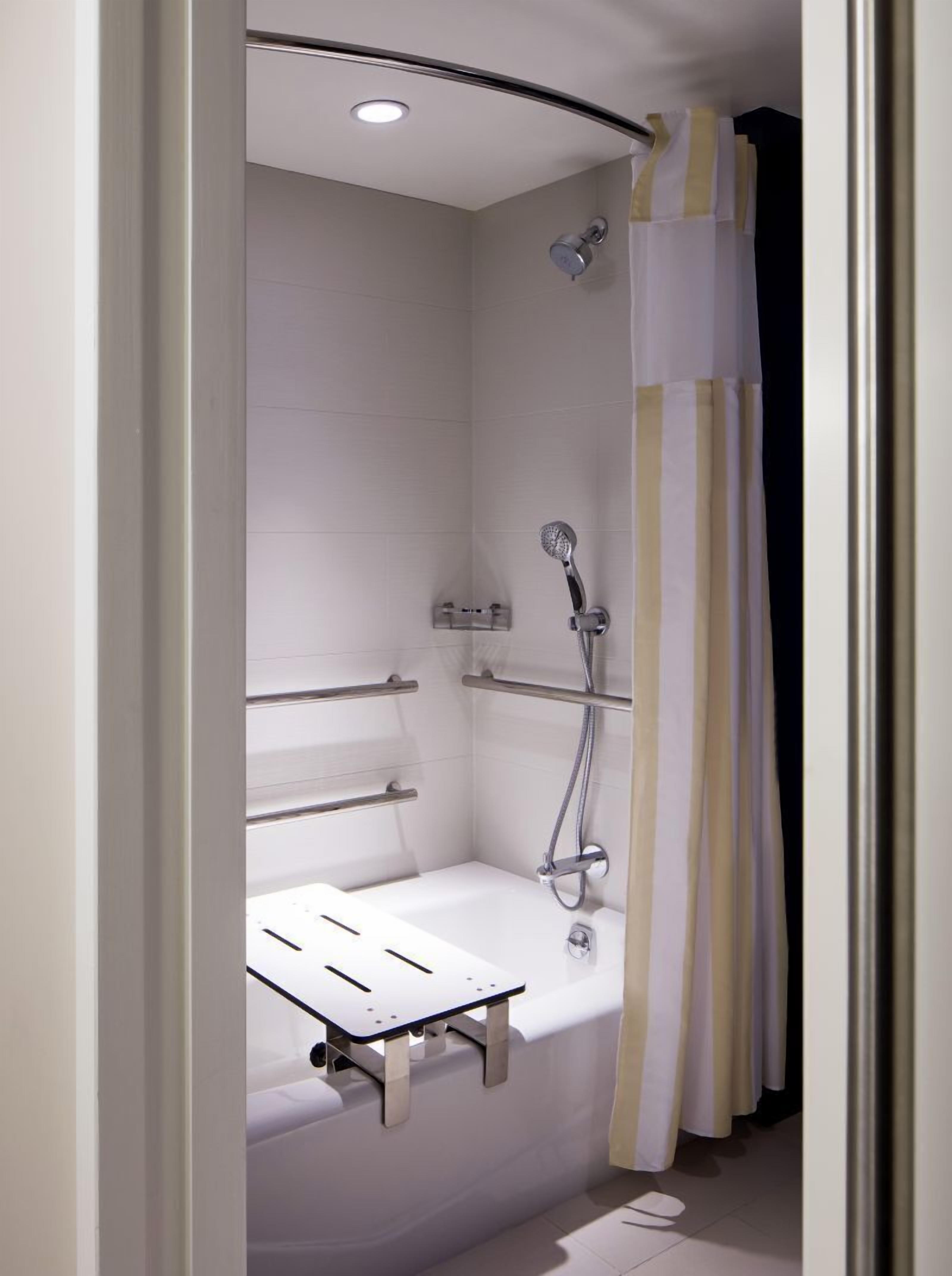 A modern shower with a handheld showerhead, a built-in seat, and a towel rack.