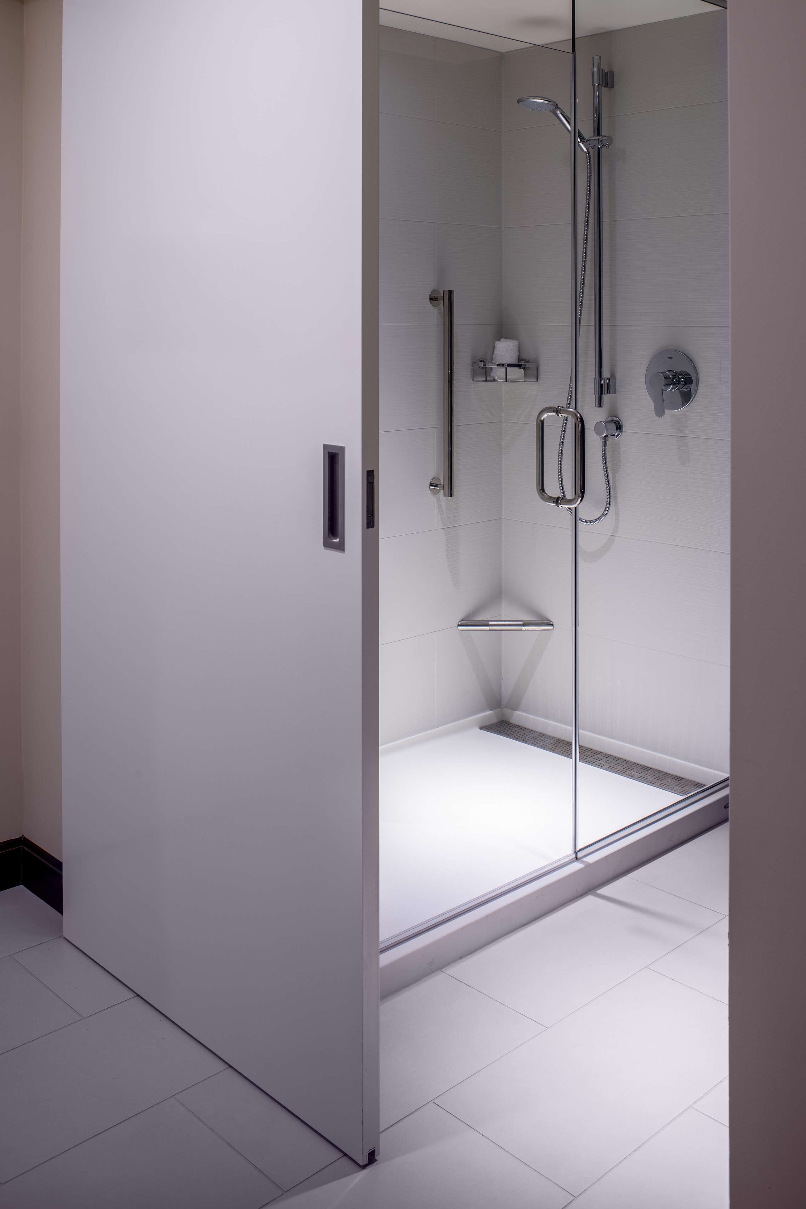 Un baño moderno con cabina de ducha de vidrio, paredes cubiertas de azulejos blancos y un diseño minimalista.