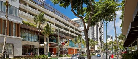 A multi-story hotel with outdoor seating and a pedestrian walkway.