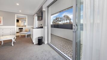 A modern interior with a sliding glass door leading to a balcony, a white sofa, a small table, and a trash bin.
