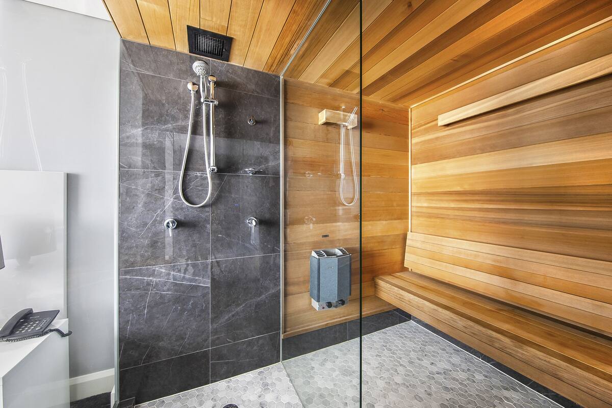 A modern bathroom with a glass-enclosed shower, a wooden wall, and a built-in heater.