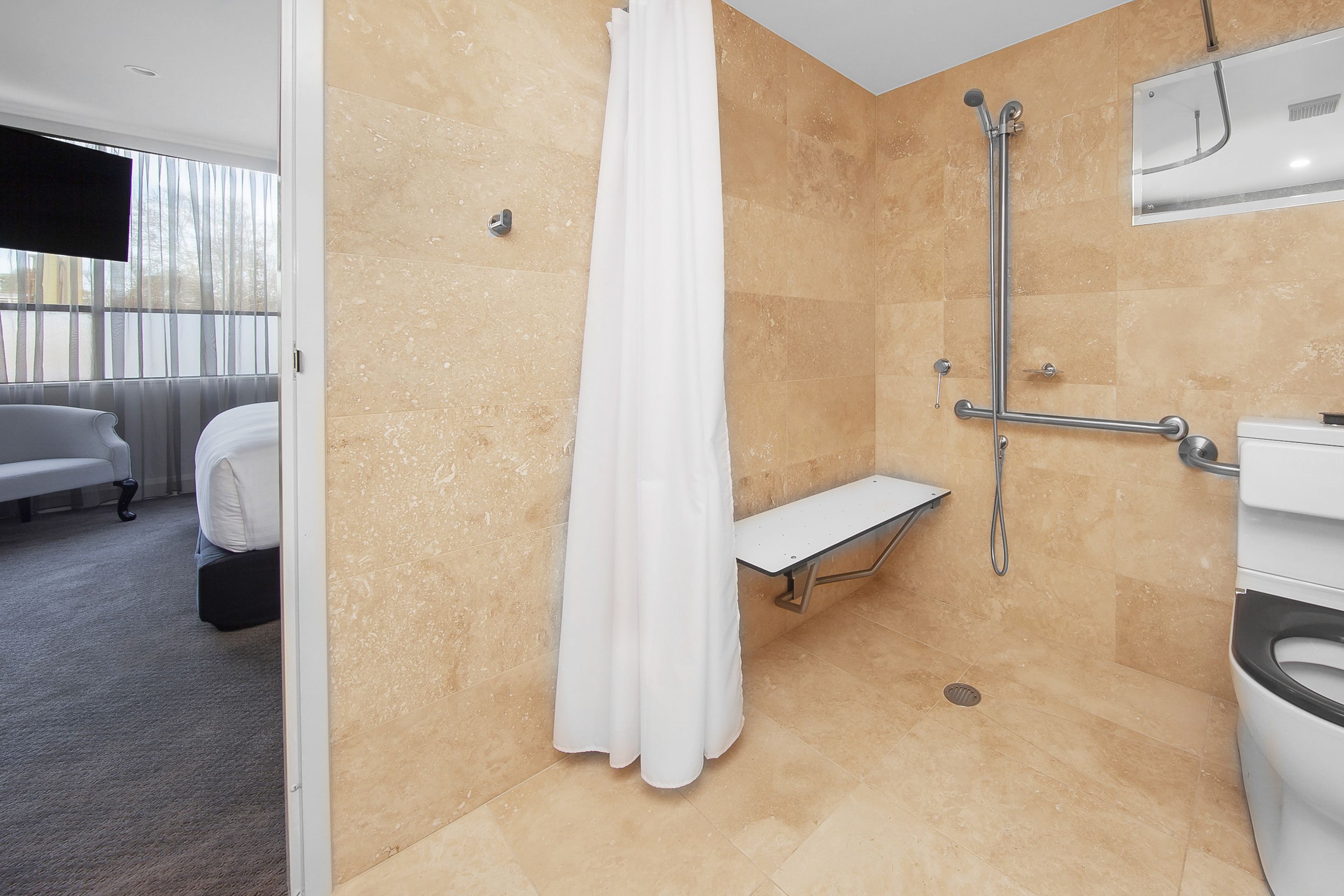Un baño moderno con ducha, un banco y un inodoro.
