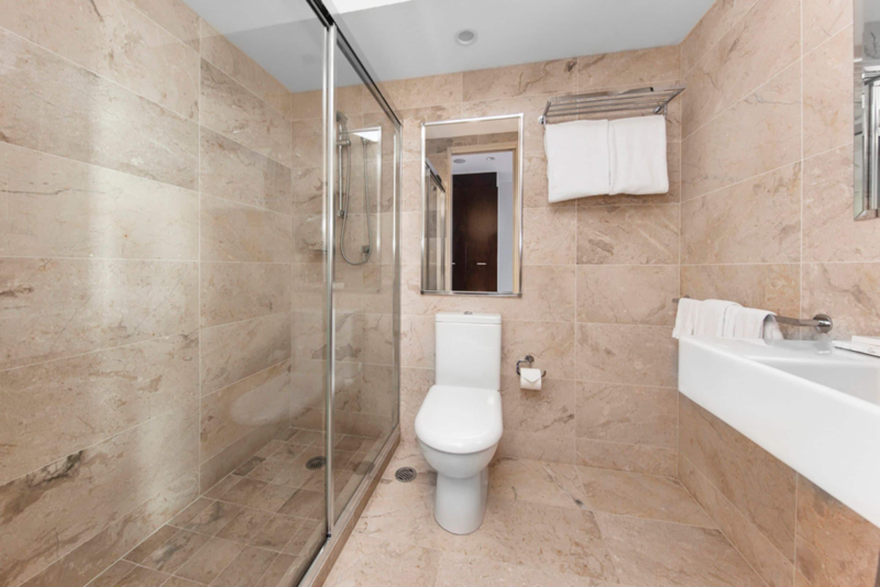 A modern bathroom with a glass-enclosed shower, a toilet, and a bathtub.