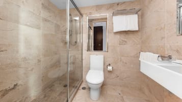 A modern bathroom with a glass-enclosed shower, a toilet, and a bathtub.