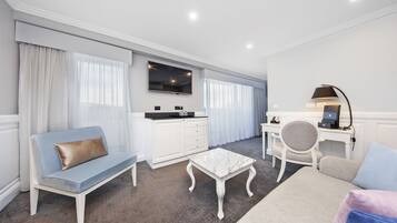 A modern hotel room with a sofa, a small table, a desk, and a chair.