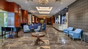 A lobby with a grand piano, blue seating, marble flooring, and a chandelier. - Canberra Rex Hotel (Braddon)