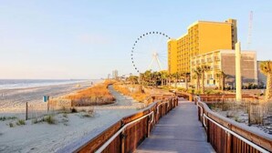 Eine Promenade führt zu einem Strandhotel, im Hintergrund ist ein Riesenrad zu sehen.