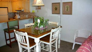 A compact kitchen with a dining table, chairs, and a hanging lamp.