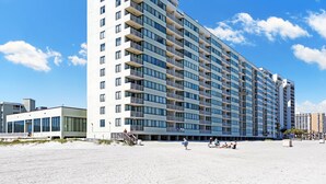 Ein mehrstöckiges Hotel mit Balkonen, großen Fenstern und einer Lage direkt am Strand.