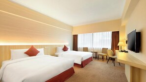 A hotel room with two beds, a TV, a desk, and a chair.