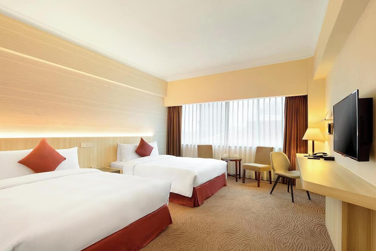 A hotel room with two beds, a TV, a desk, and a chair.