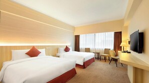 Une chambre d’hôtel avec deux lits, une télévision, un bureau et une chaise.