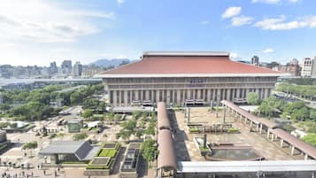 A large, modern building with a red roof and a spacious plaza in front.