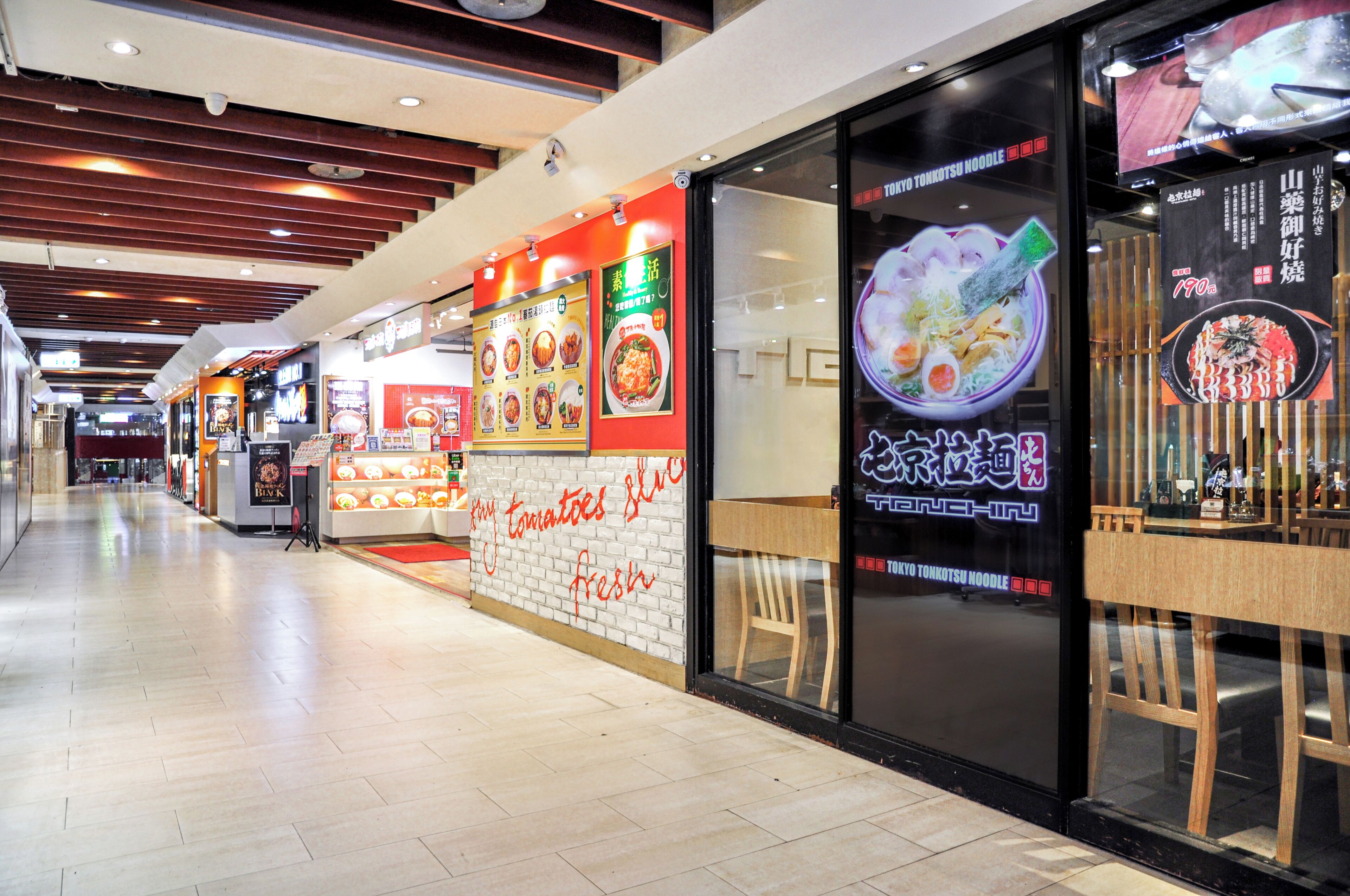 A restaurant with a modern interior, featuring a counter with a menu display and a seating area with chairs.