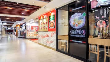 A restaurant with a modern interior, featuring a counter with a menu display and a seating area with chairs.