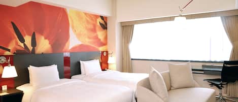 A hotel room with two beds, a sofa, a glass table with fruit, a lamp, and a large window with curtains.