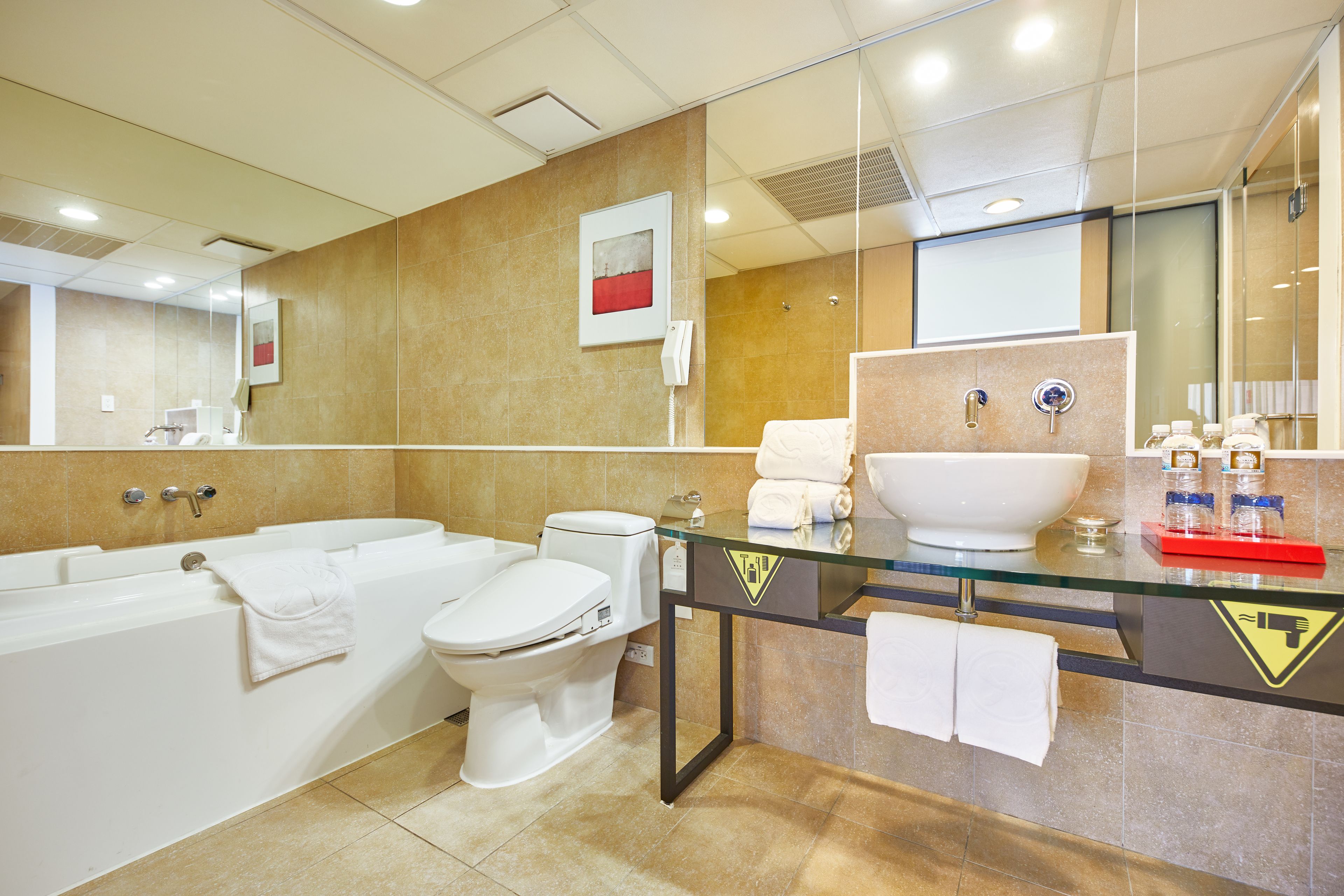 A modern bathroom with a glass-enclosed vanity, a bathtub, and a toilet.