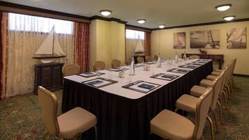 Un salón de conferencias con una mesa larga, sillas y una lámpara.
