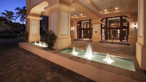 A hotel entrance with a fountain, a covered walkway, and a grand entrance with glass doors. - Jupiter Beach Resort & Spa (Jupiter)