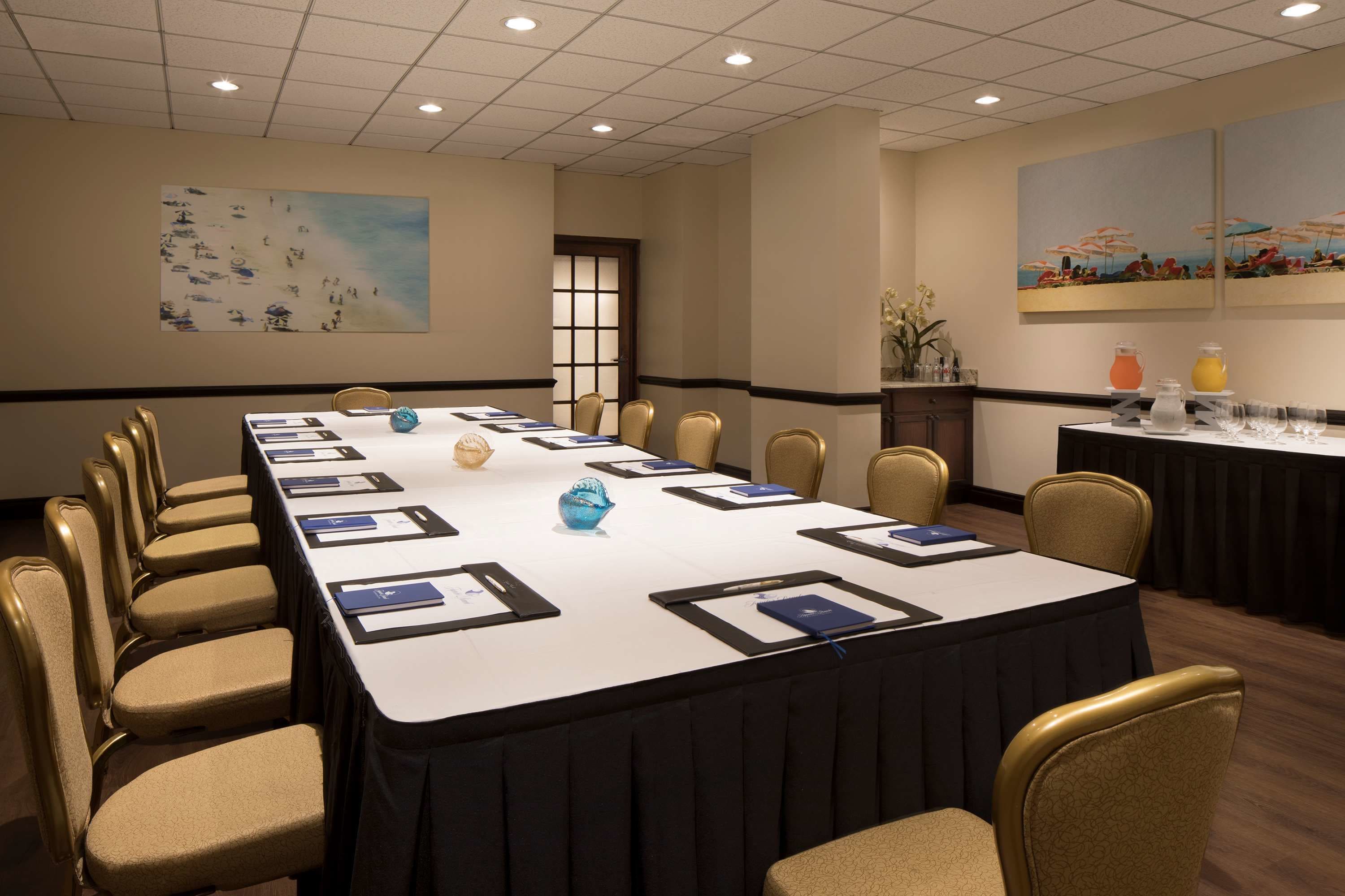 Une salle de conférence avec une longue table, des chaises et un tableau accroché au mur.