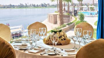 Una mesa lista para comer, con vistas a un lago y una piscina.