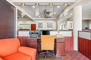 A hotel room with a wooden desk, a computer, a chair, and a large window.