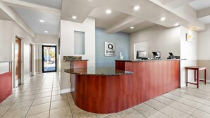 A reception area with a curved wooden counter, a sign reading "Quality by Choice," and a computer monitor. - Quality Inn Weeki Wachee - Spring Hill (Brooksville)