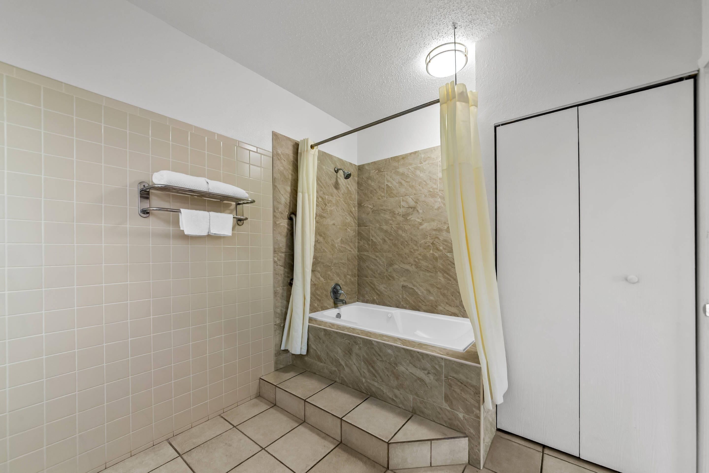 A bathroom with a bathtub, a shower curtain, and a towel rack.