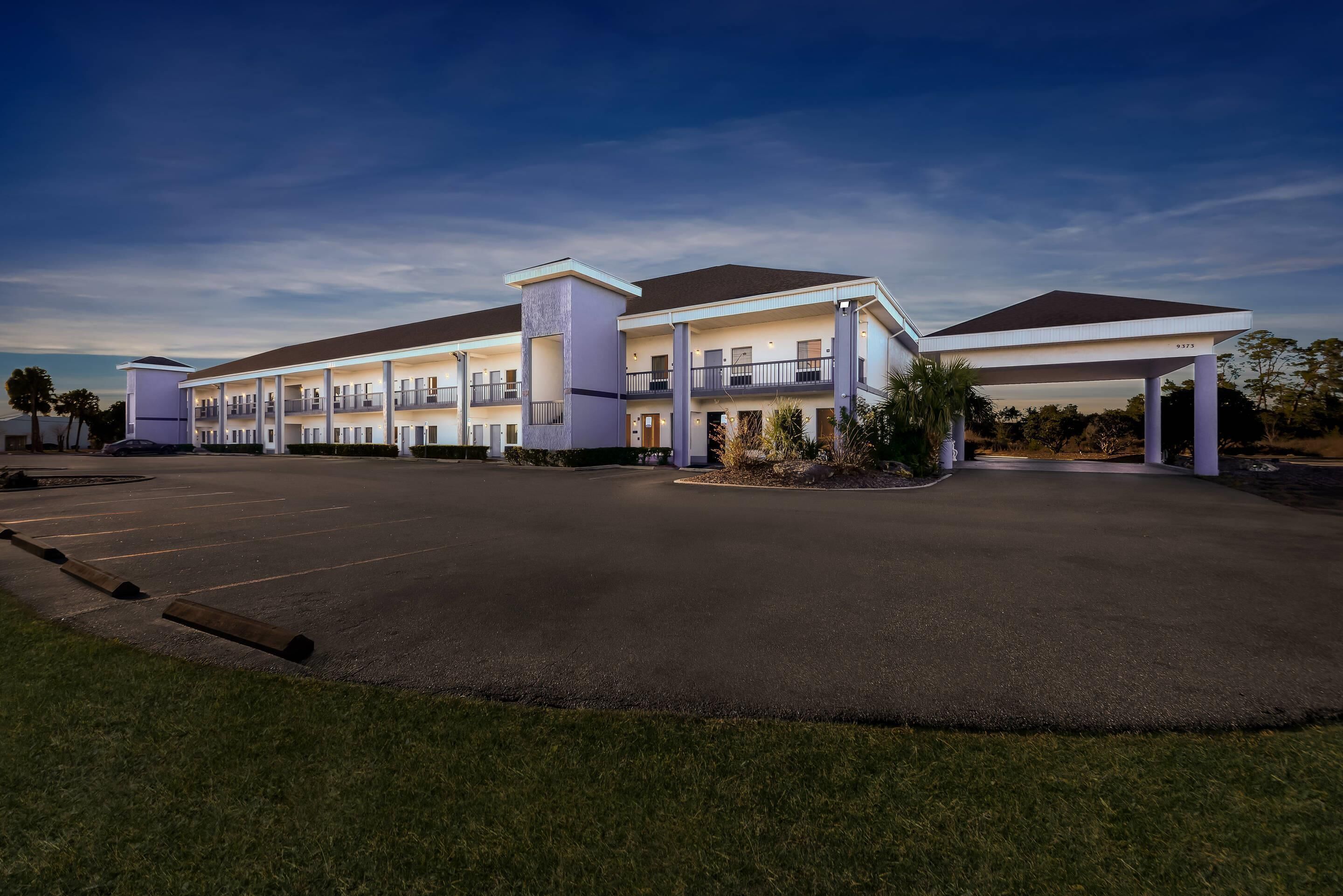 A modern hotel with a two-story structure, a covered parking area, and a landscaped entrance.