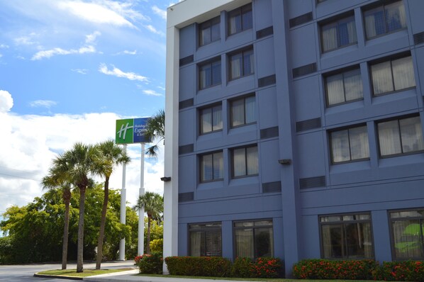 A modern hotel building with a blue facade, multiple windows, and a sign indicating it is a Holiday Inn Express.