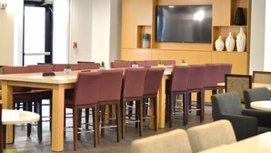 A conference room with a large flat-screen TV, wooden tables, and chairs.