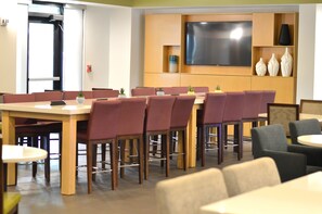A conference room with a large flat-screen TV, wooden tables, and chairs. - Holiday Inn Express & Suites Miami - Hialeah by IHG (Hialeah)